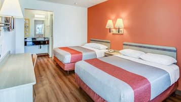 Ein Hotelzimmer mit zwei Betten, einem Schreibtisch und einem durch eine offene Tür einsehbarer Badezimmer.