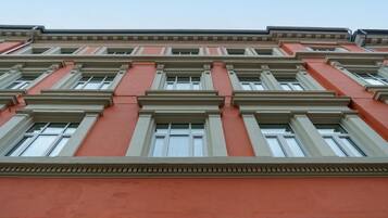 Un edificio de varios pisos con fachada roja y marcos de ventanas blancos.