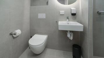 Un baño moderno con inodoro, lavamanos y espejo.
