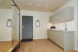 A modern kitchen with a marble countertop, a built-in sink, and a door leading to another room. - MAYA Apartments - Vika (Oslo)