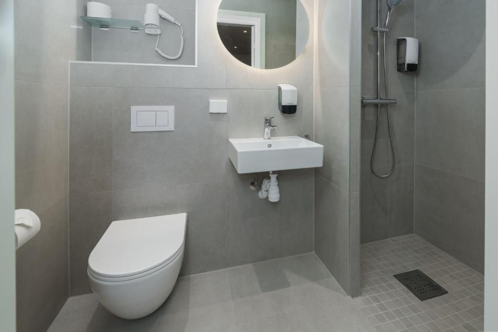 Un baño moderno con inodoro, lavamanos y ducha.