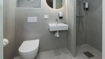 Un baño moderno con inodoro, lavamanos y ducha.