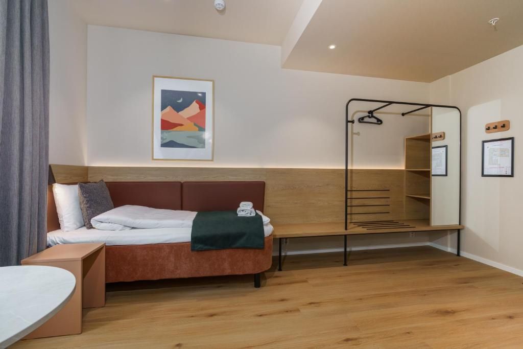 A modern hotel room with a bed, a bench, a hanging chair, and a wall-mounted shelf.