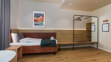 A modern hotel room with a bed, a bench, a hanging chair, and a wall-mounted shelf.
