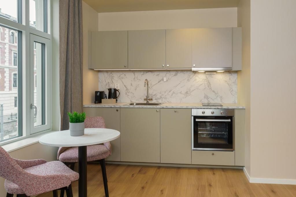 A modern kitchen with a marble backsplash, stainless steel appliances, and a window with a view of buildings.