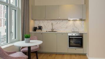 A modern kitchen with a marble backsplash, stainless steel appliances, and a window with a view of buildings.