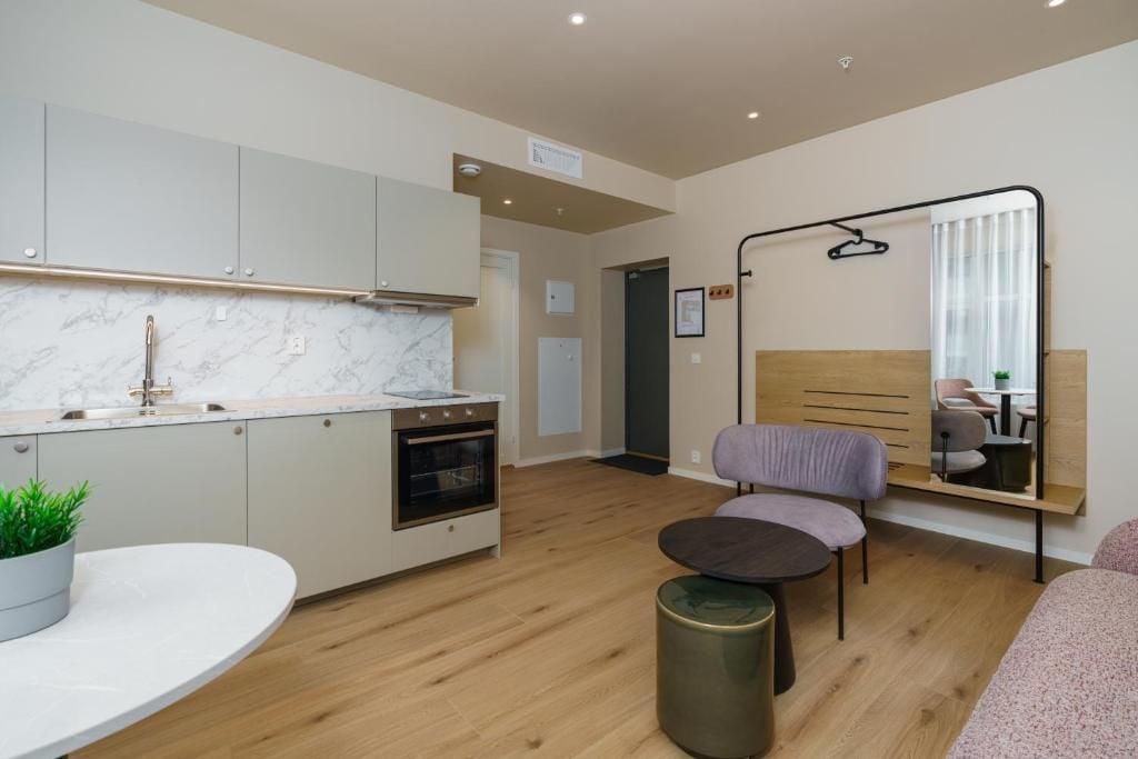 A modern kitchen with a marble countertop, a built-in oven, and a dining area with a round table and chairs.