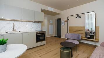 A modern kitchen with a marble countertop, a built-in oven, and a dining area with a round table and chairs.