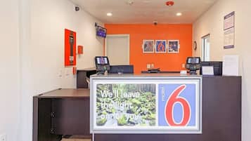 A reception desk with a digital display, a number 6 sign, and a wall-mounted fire extinguisher.
