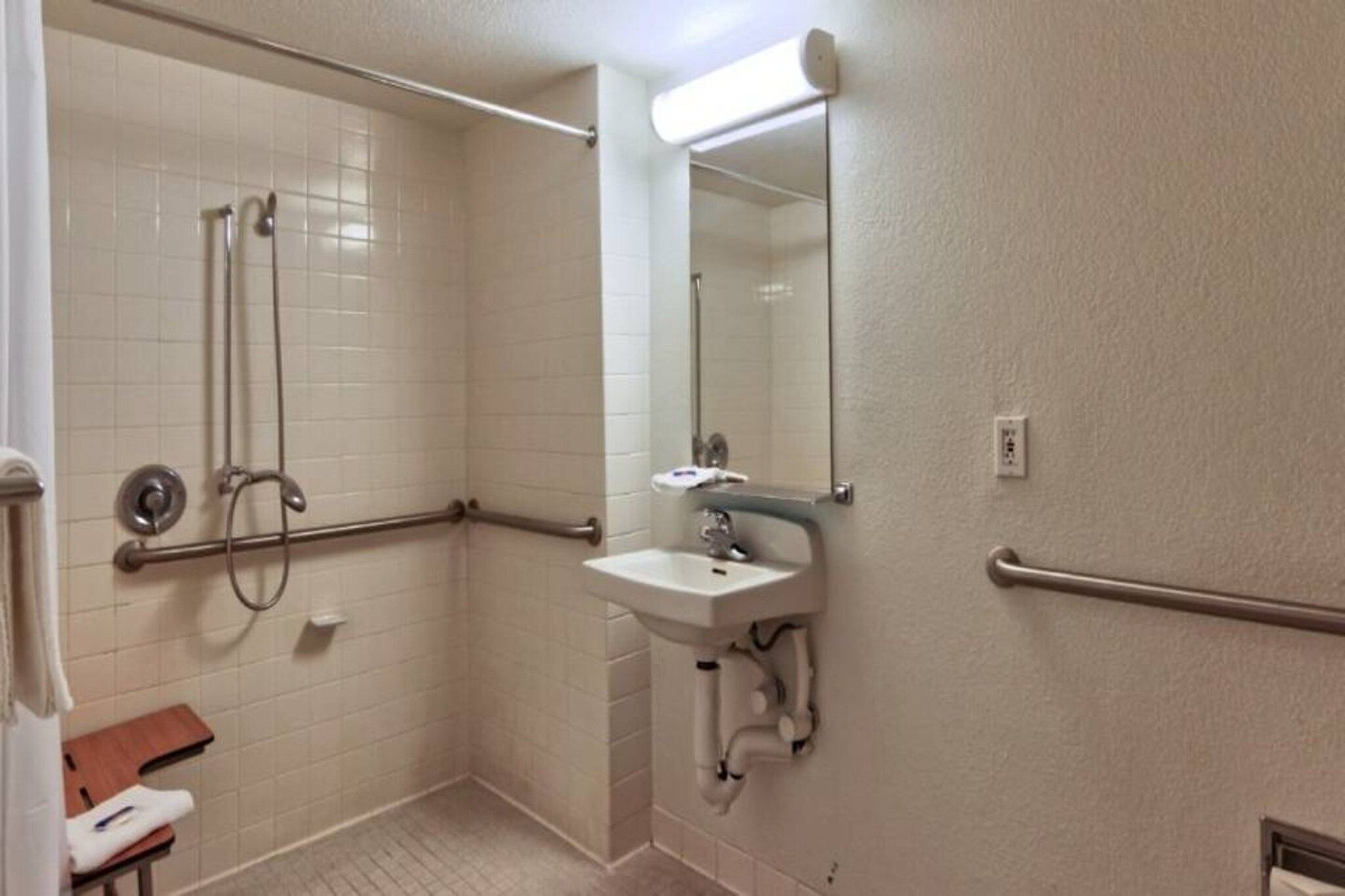 A bathroom with a shower, a sink, and a mirror.