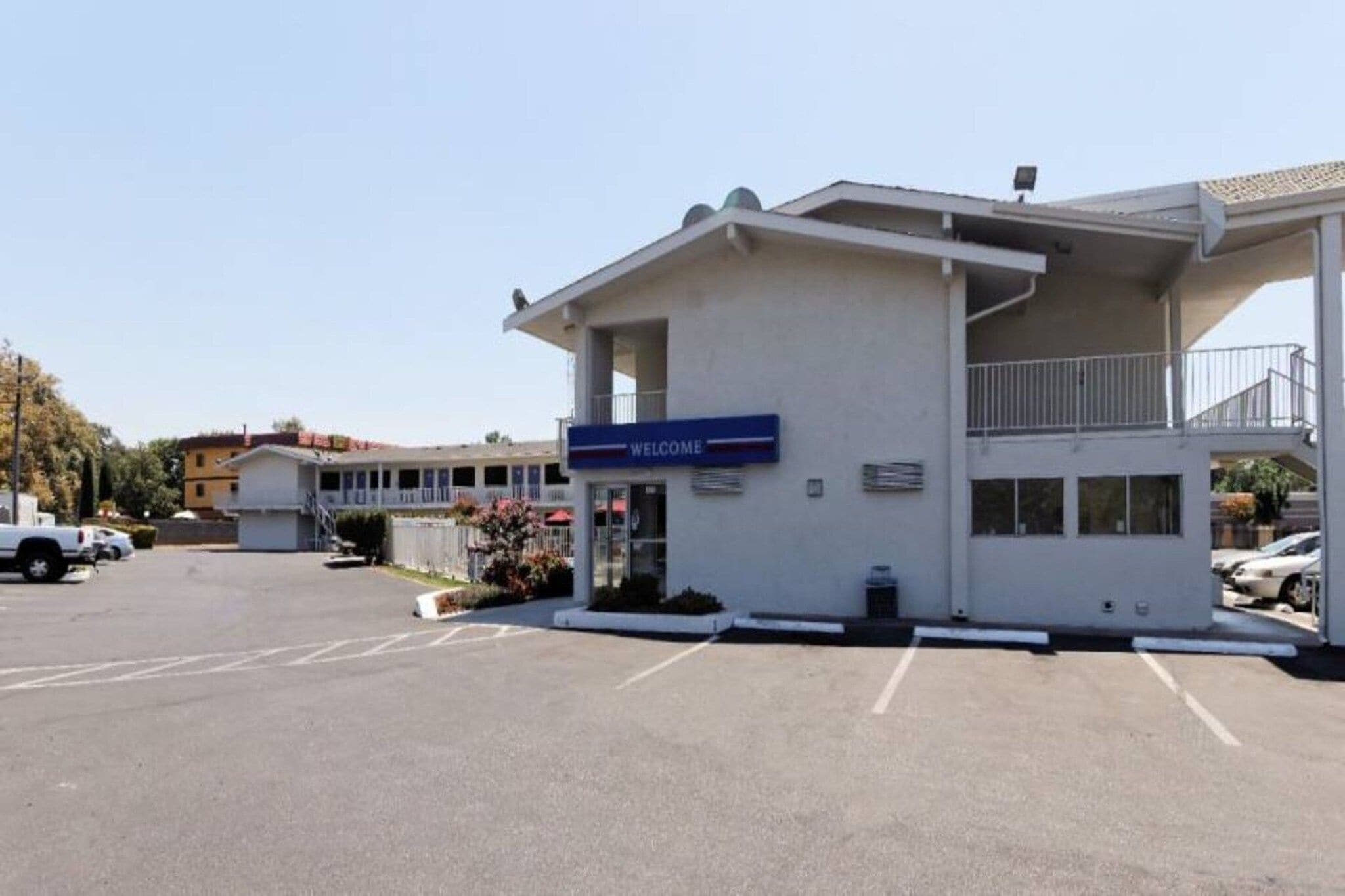 A building with a 'WELCOME' sign, a covered entrance, and a parking lot.