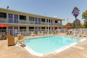 Ein Motel mit Schwimmbad, mehreren Balkonen und roten Sonnenschirmen.