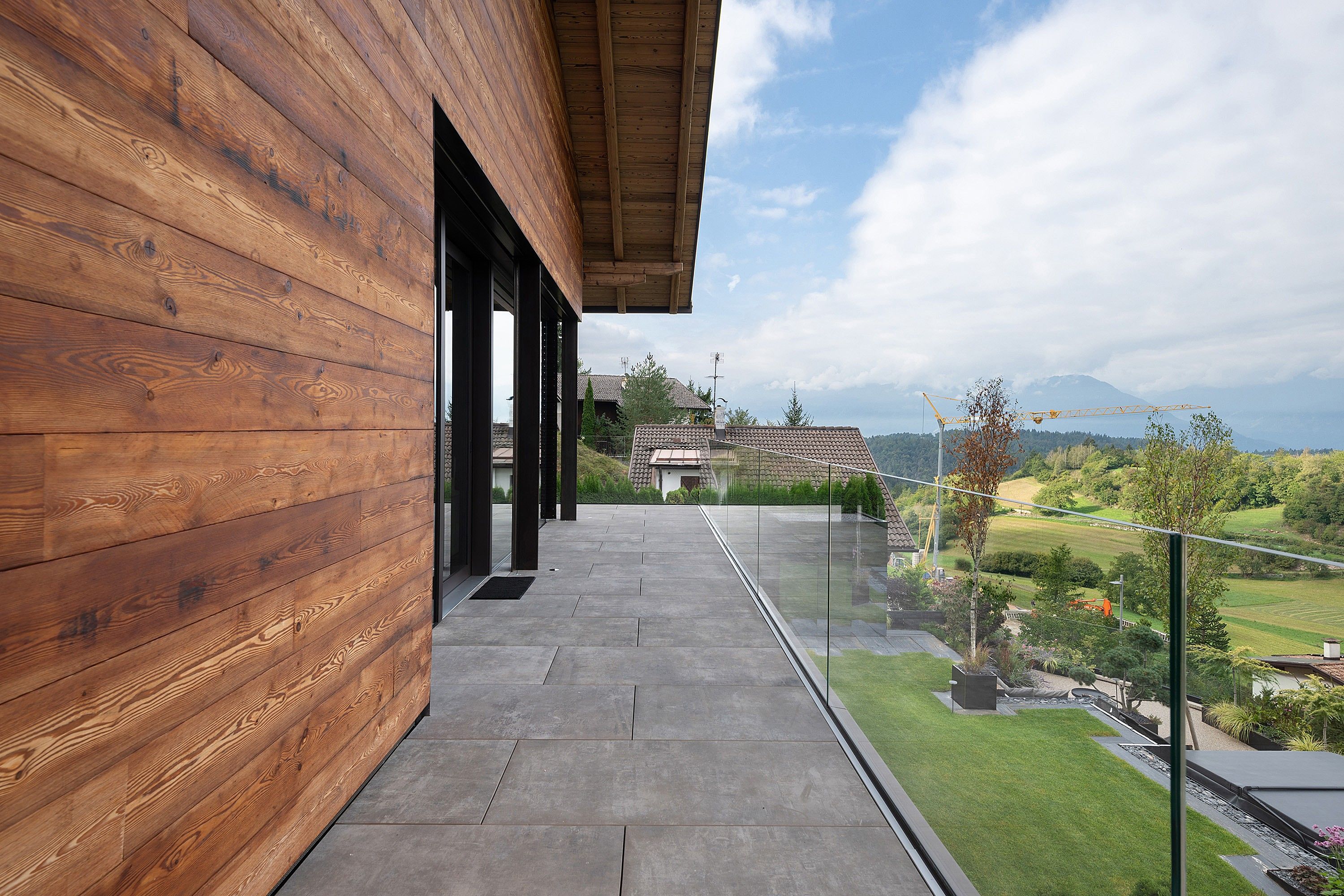 A modern building with a wooden facade and a balcony overlooking a scenic landscape.