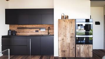 Una cucina moderna con mobili scuri, un piano di lavoro in legno e un forno integrato.