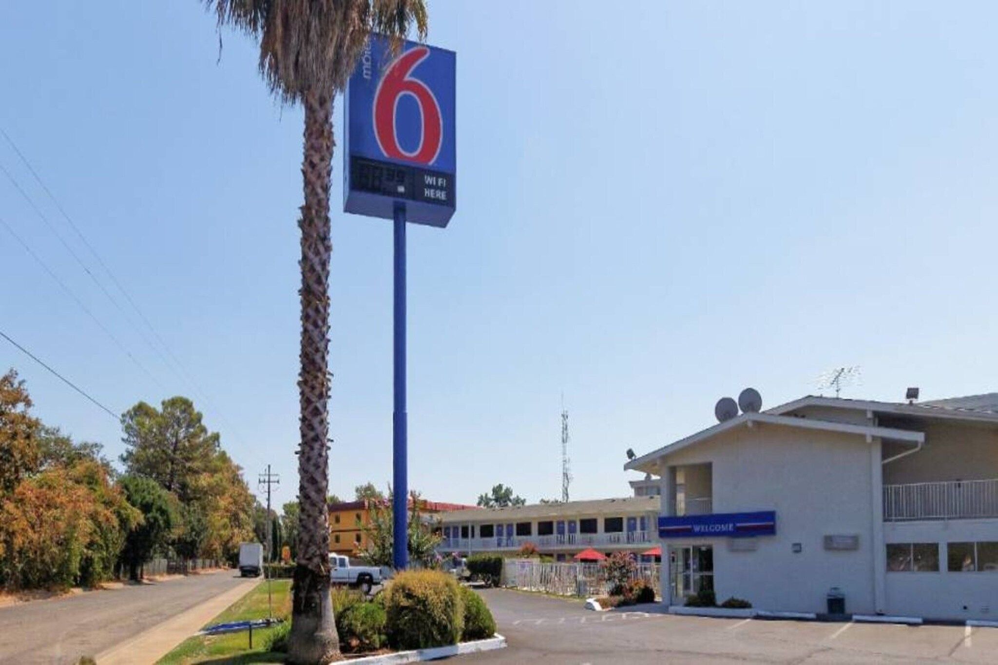 A motel with a prominent '6' sign, a parking lot, and a building with a 'WELCOME' sign.