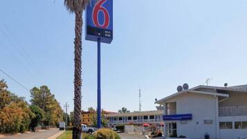 A motel with a prominent '6' sign, a parking lot, and a building with a 'WELCOME' sign.