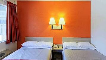 Habitación de hotel con dos camas, una lámpara de pared y un ventanal con cortinas.