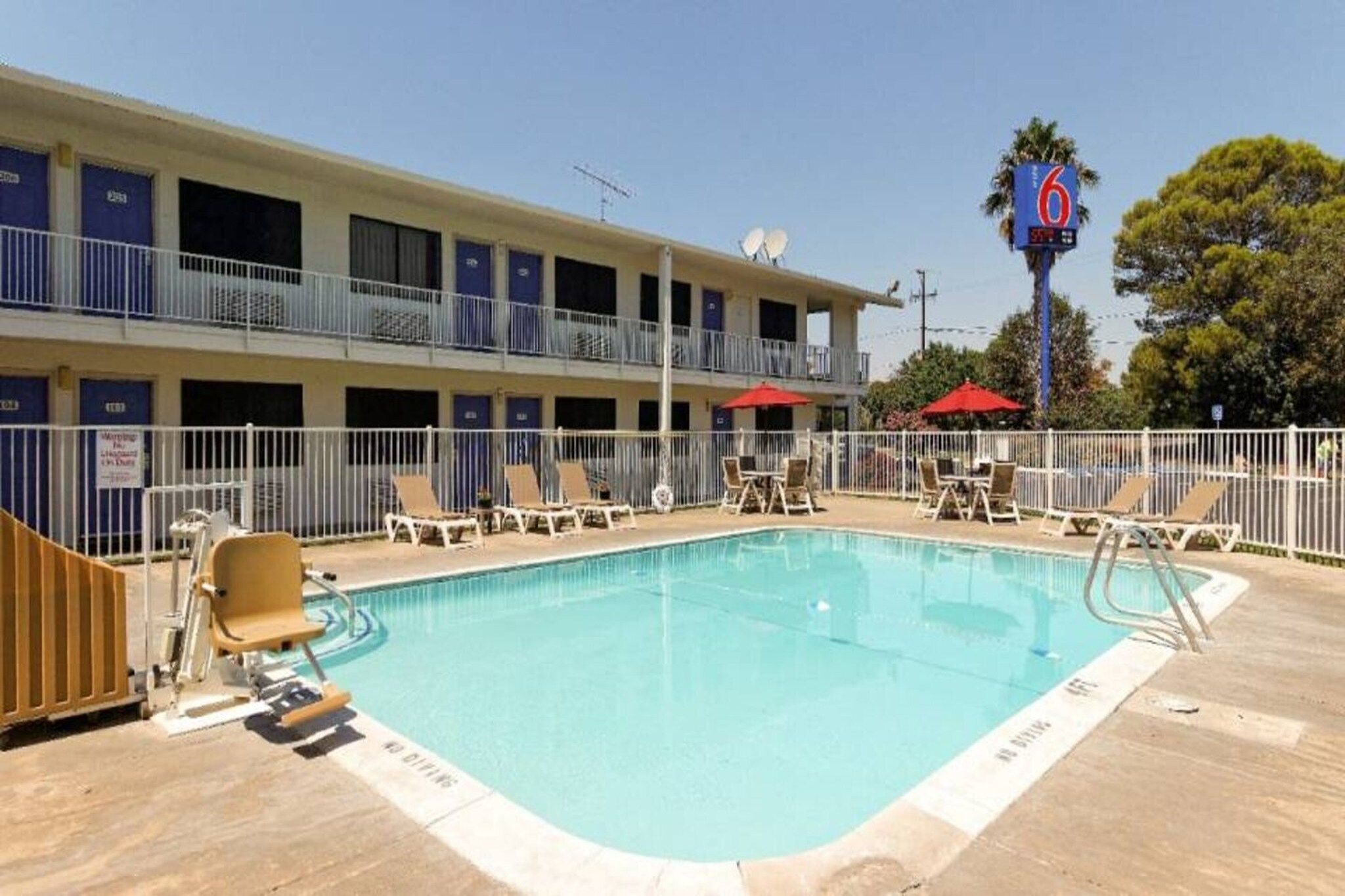 A hotel with a swimming pool, multiple balconies, and a sign indicating room number 6.