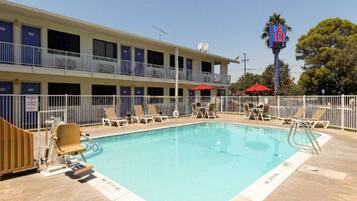 A hotel with a swimming pool, multiple balconies, and a sign indicating room number 6.
