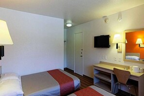 A hotel room with two beds, a desk, a chair, a television, and a bathroom door.
