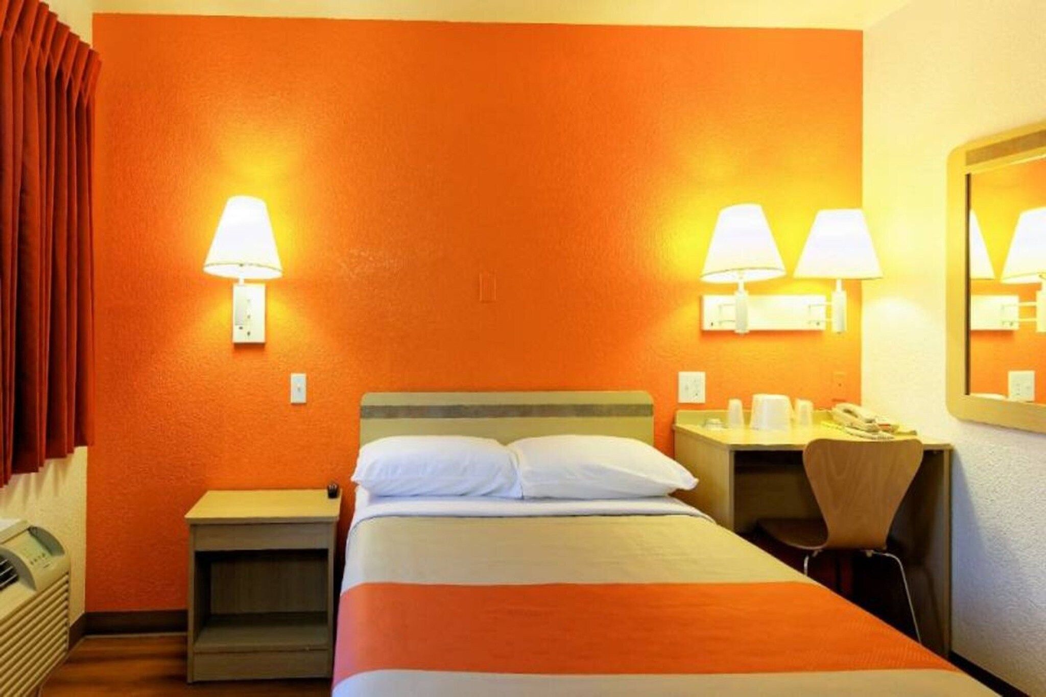 Ein Hotelzimmer mit einem Bett, zwei Nachttischen, einem Schreibtisch mit Stuhl und einem Spiegel.