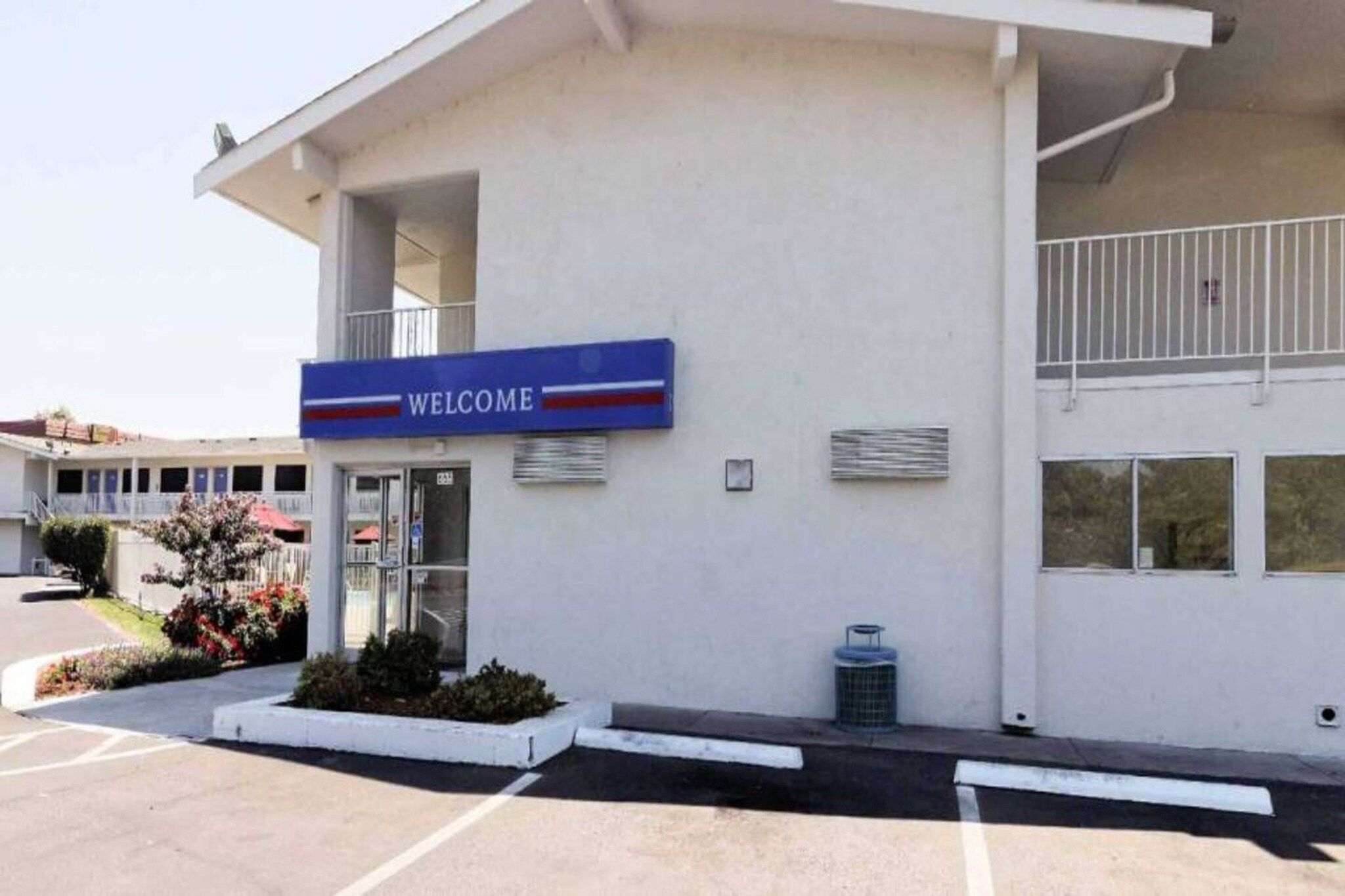 A building with a 'WELCOME' sign, a covered entrance, and a parking lot.