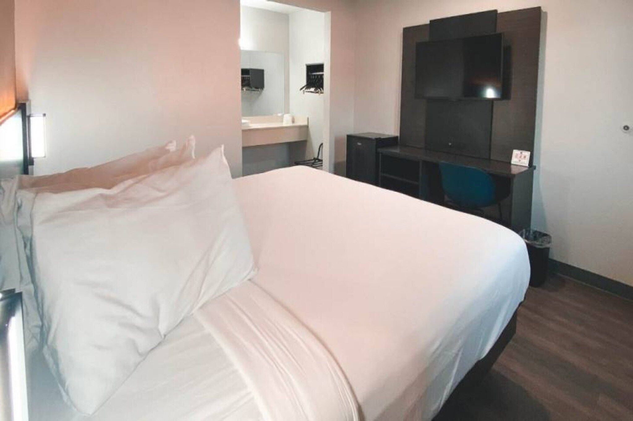 Habitación de hotel con cama, escritorio, espejo y televisión.