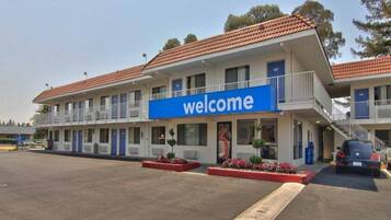 A motel with a 'welcome' sign, multiple balconies, and a parking area.