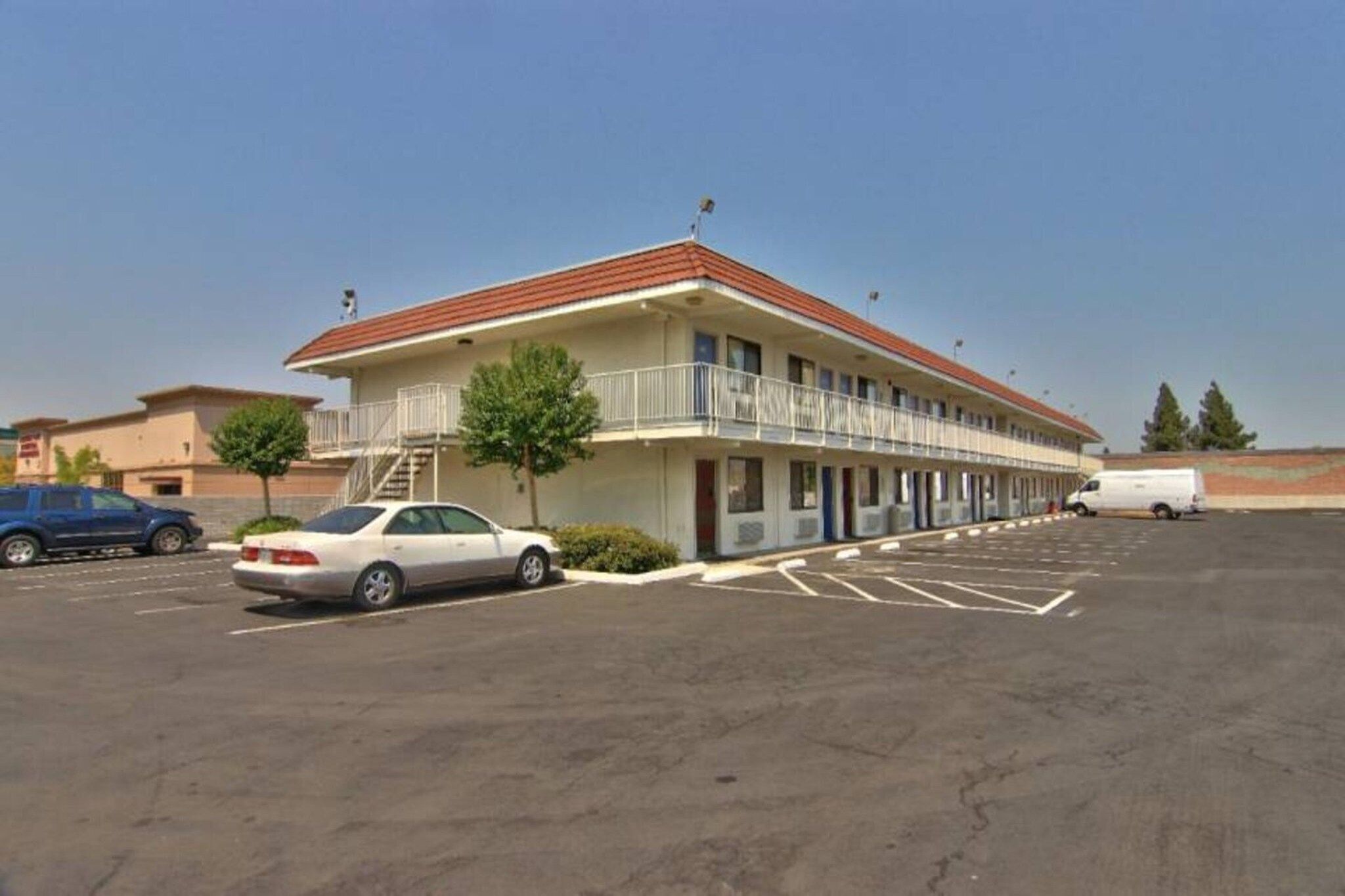A motel with a two-story structure, a parking lot, and a white van parked in front.