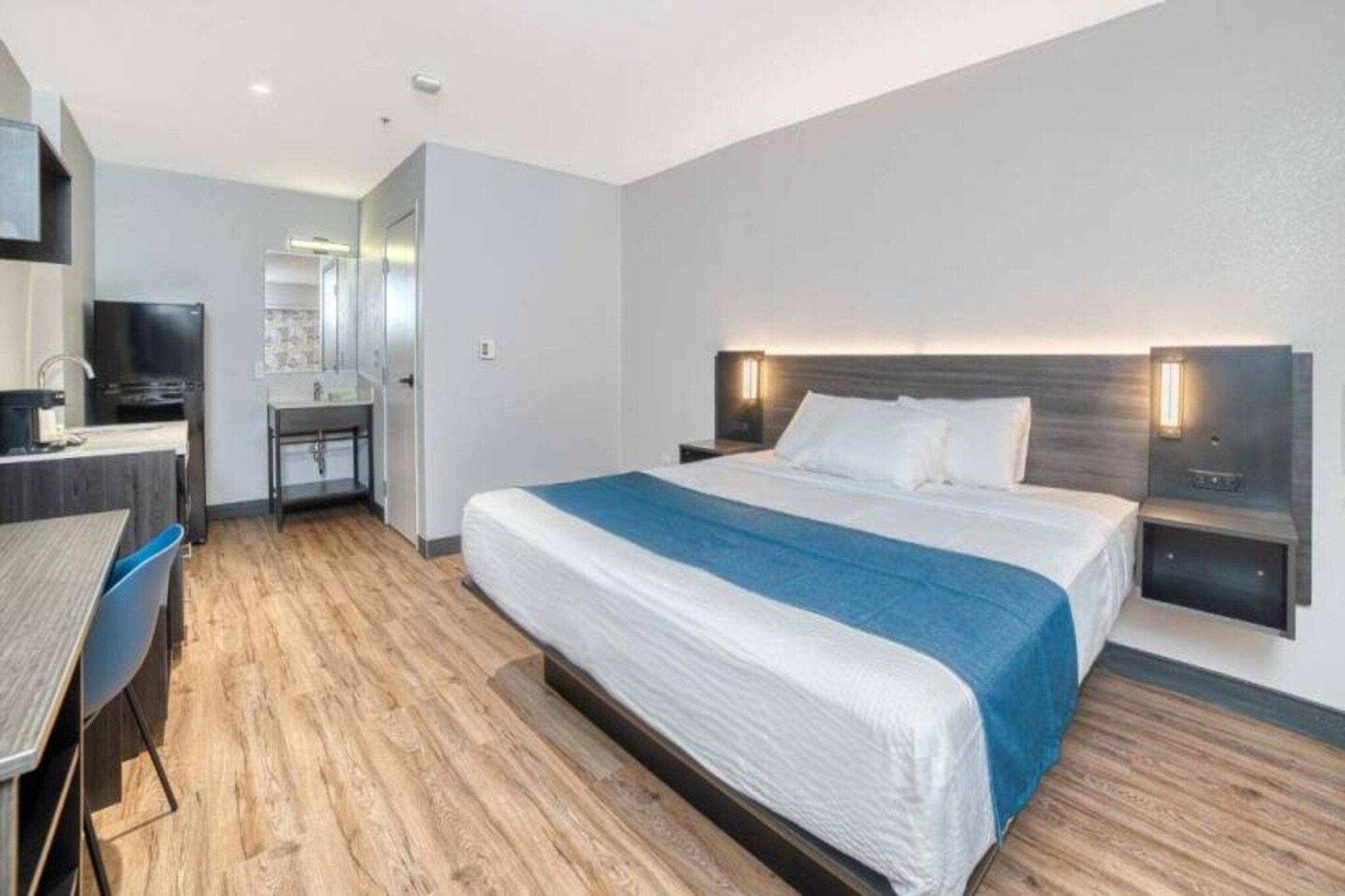 Ein modernes Hotelzimmer mit Bett, Nachttischen, Schreibtisch und Stuhl.