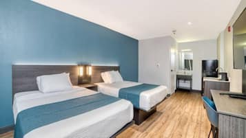 A hotel room with two beds, a desk, and a mirror.
