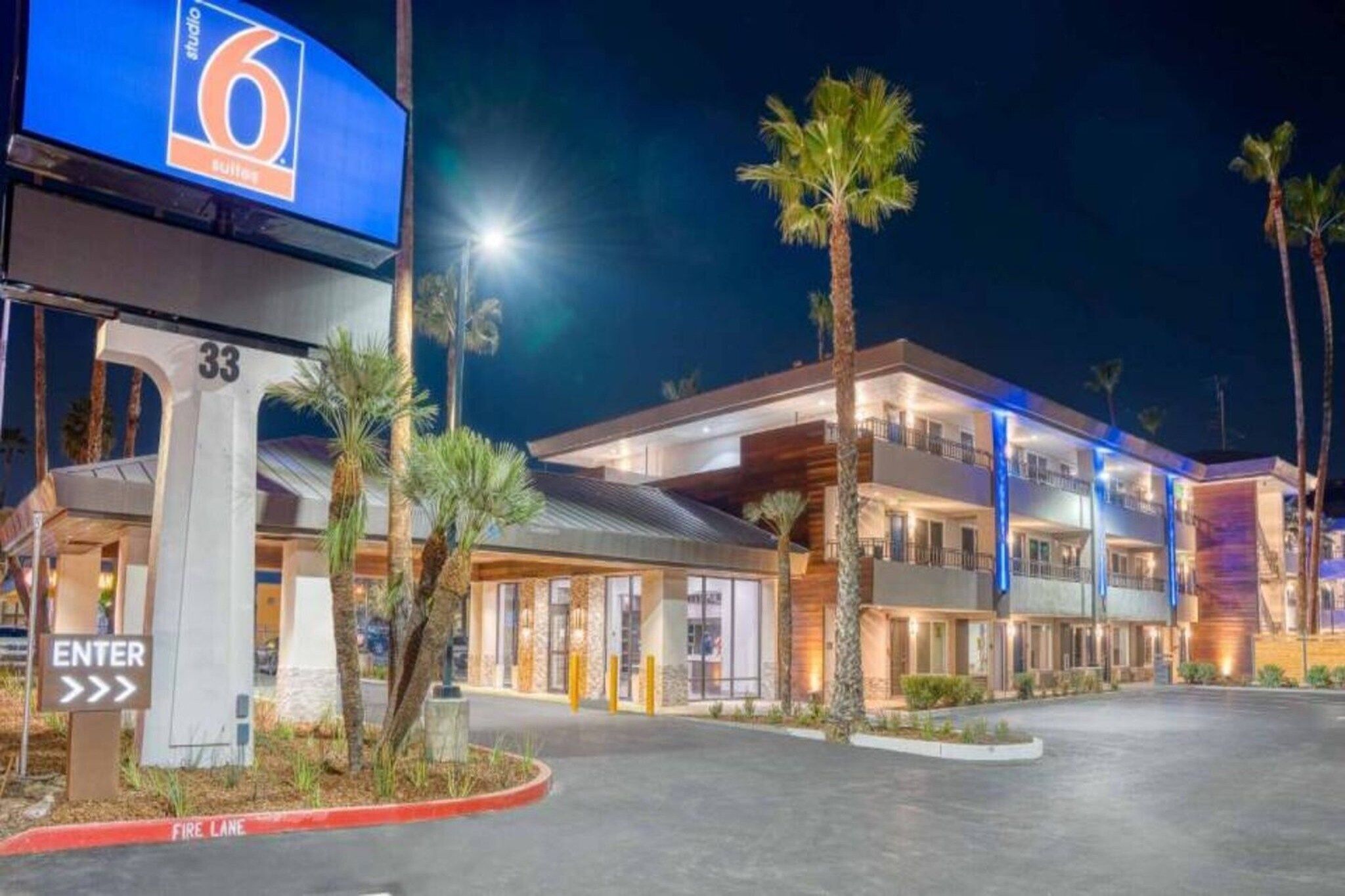 A hotel with a modern design, featuring a prominent entrance with a sign, a fire lane, and a well-lit facade.