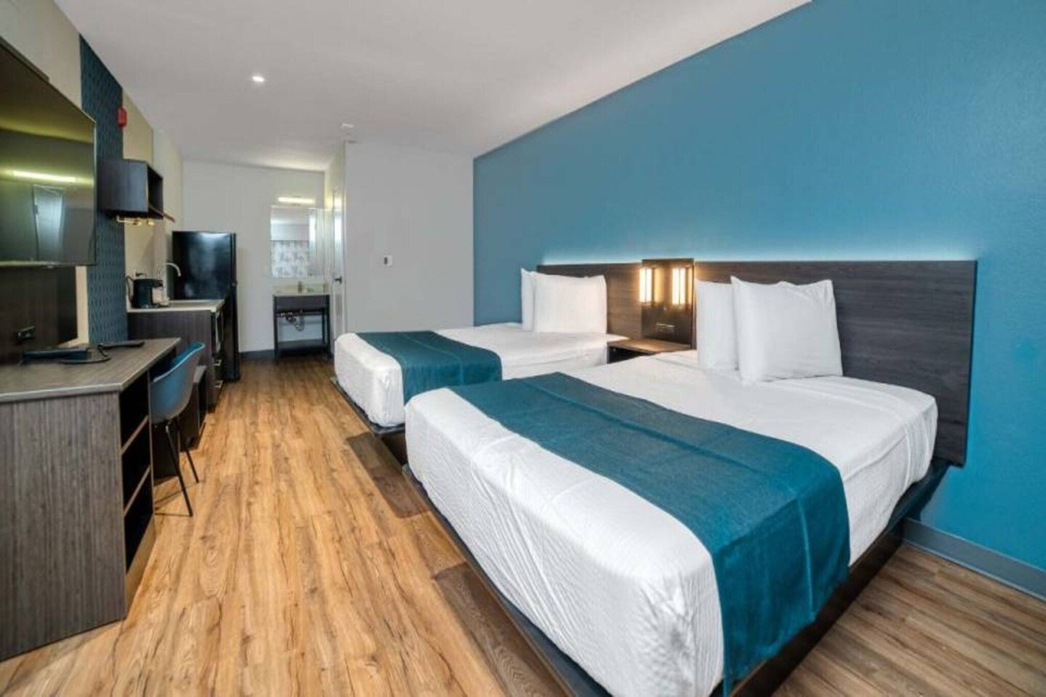 A hotel room with two beds, a desk, and a television.