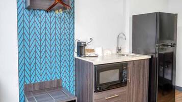 Una kitchenette compacta con microondas, cafetera y refrigerador.