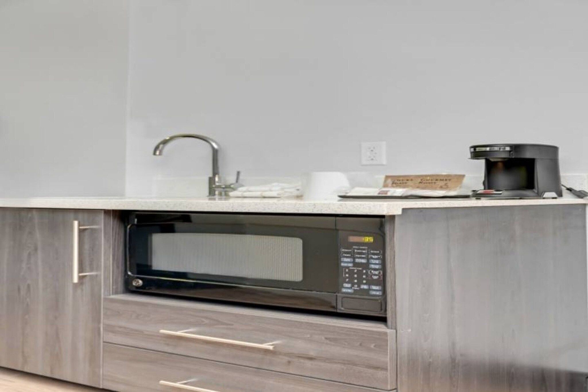 A kitchen with a built-in microwave, a coffee maker, and a sink.