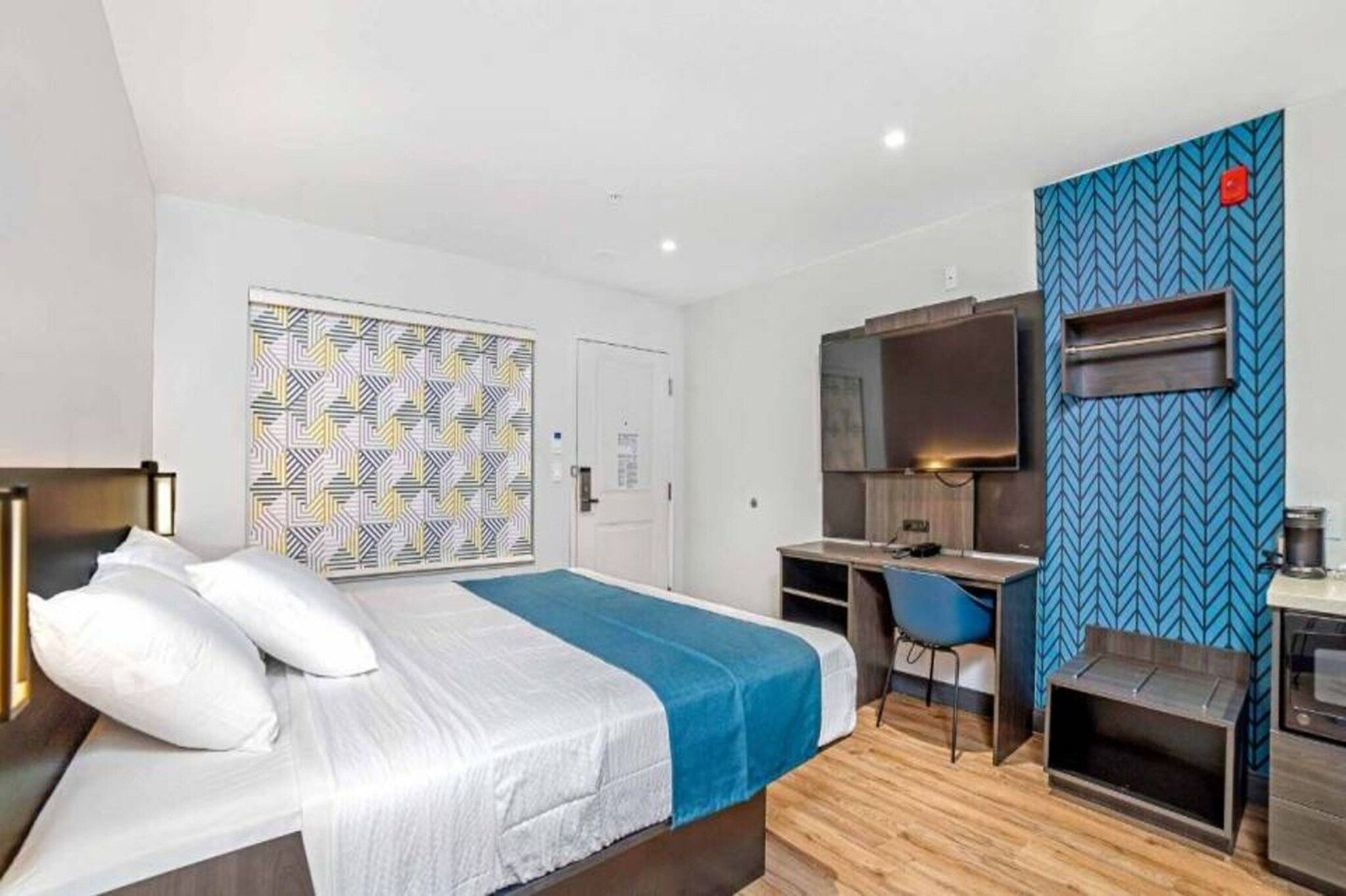 Ein Hotelzimmer mit Bett, Schreibtisch, Fernseher und einer Mikrowelle.