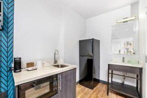 Cocina compacta equipada con microondas, cafetera y refrigerador.