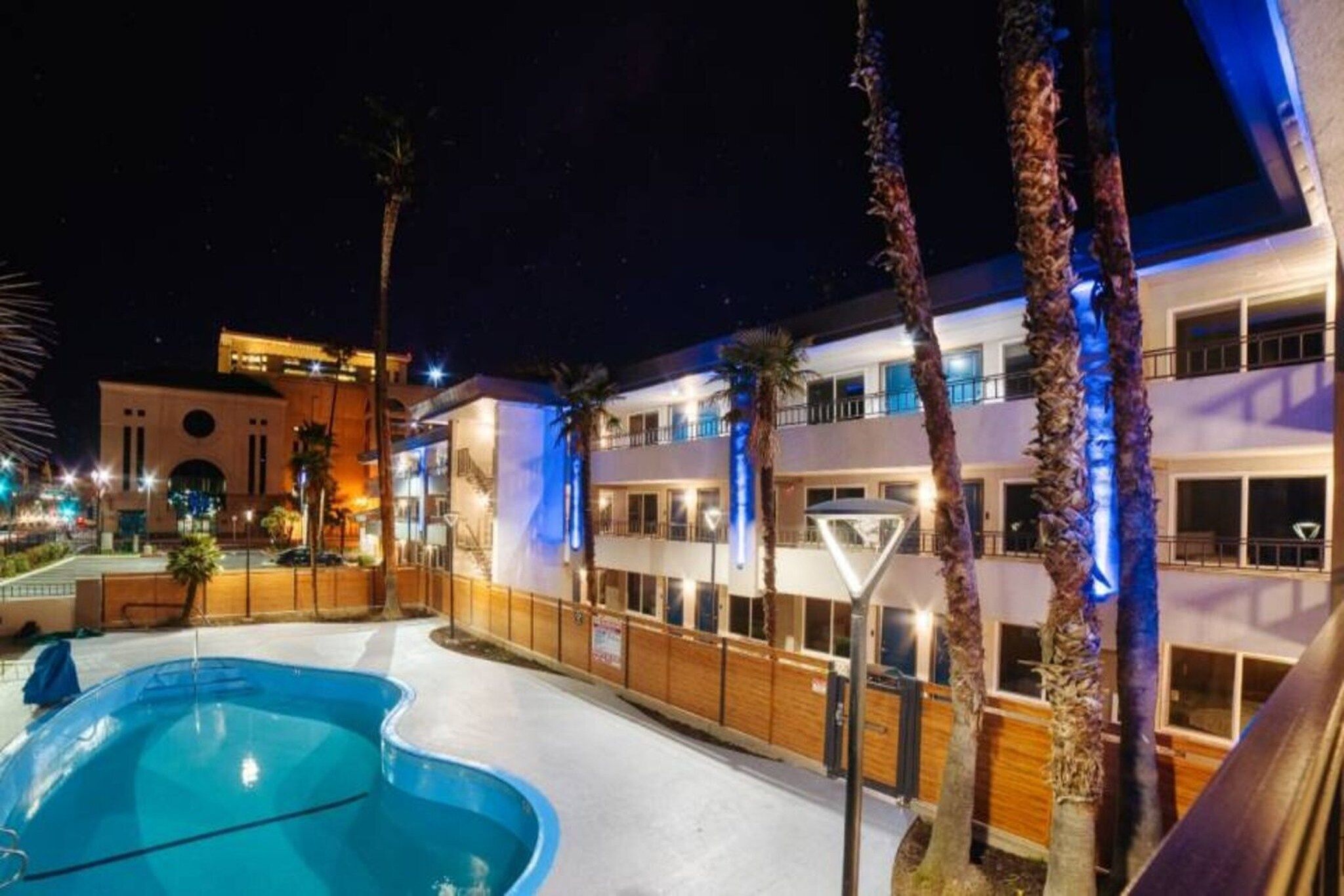 A hotel with a swimming pool, multiple balconies, and a well-lit exterior.