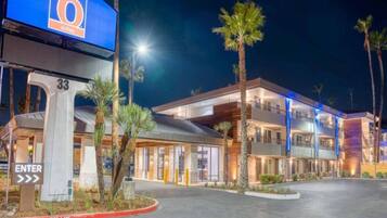A hotel with a modern design, featuring a prominent entrance with a sign, a fire lane, and a well-lit facade.