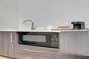 A kitchen with a built-in microwave, a coffee maker, and a sink.