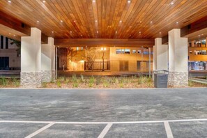 A building entrance with a wooden ceiling, stone pillars, and a paved driveway.