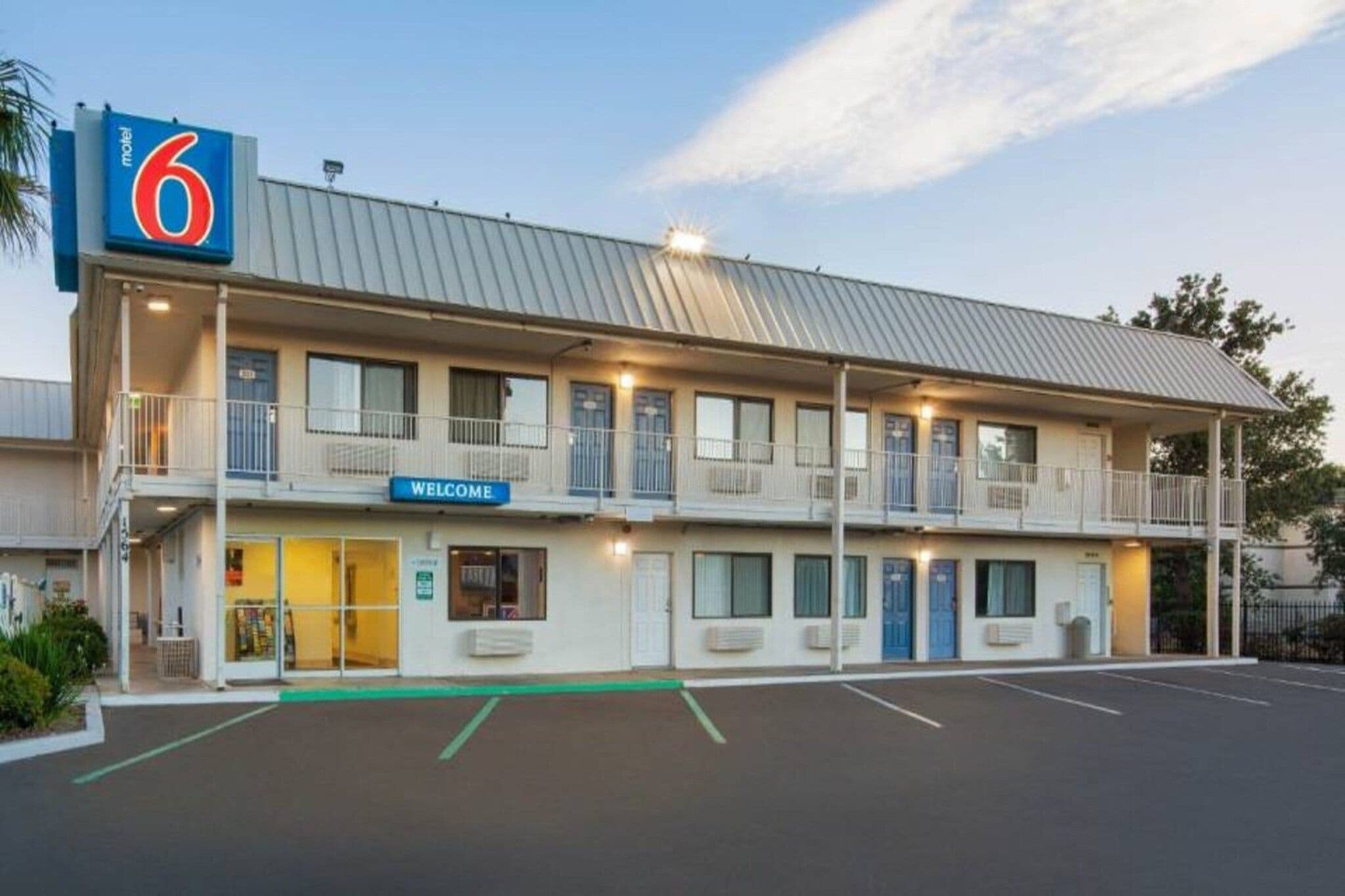 A motel with a '6' sign, a 'Welcome' sign, and a parking lot.