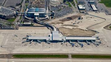 An airport terminal with multiple jet bridges, a central building, and a parking area.