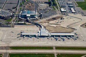 Terminal de aeroporto com diversas pontes de embarque, um edifício central e uma área de estacionamento.