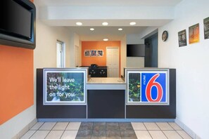 A hotel reception area with a counter, a door, and a wall with a number '6' sign.
