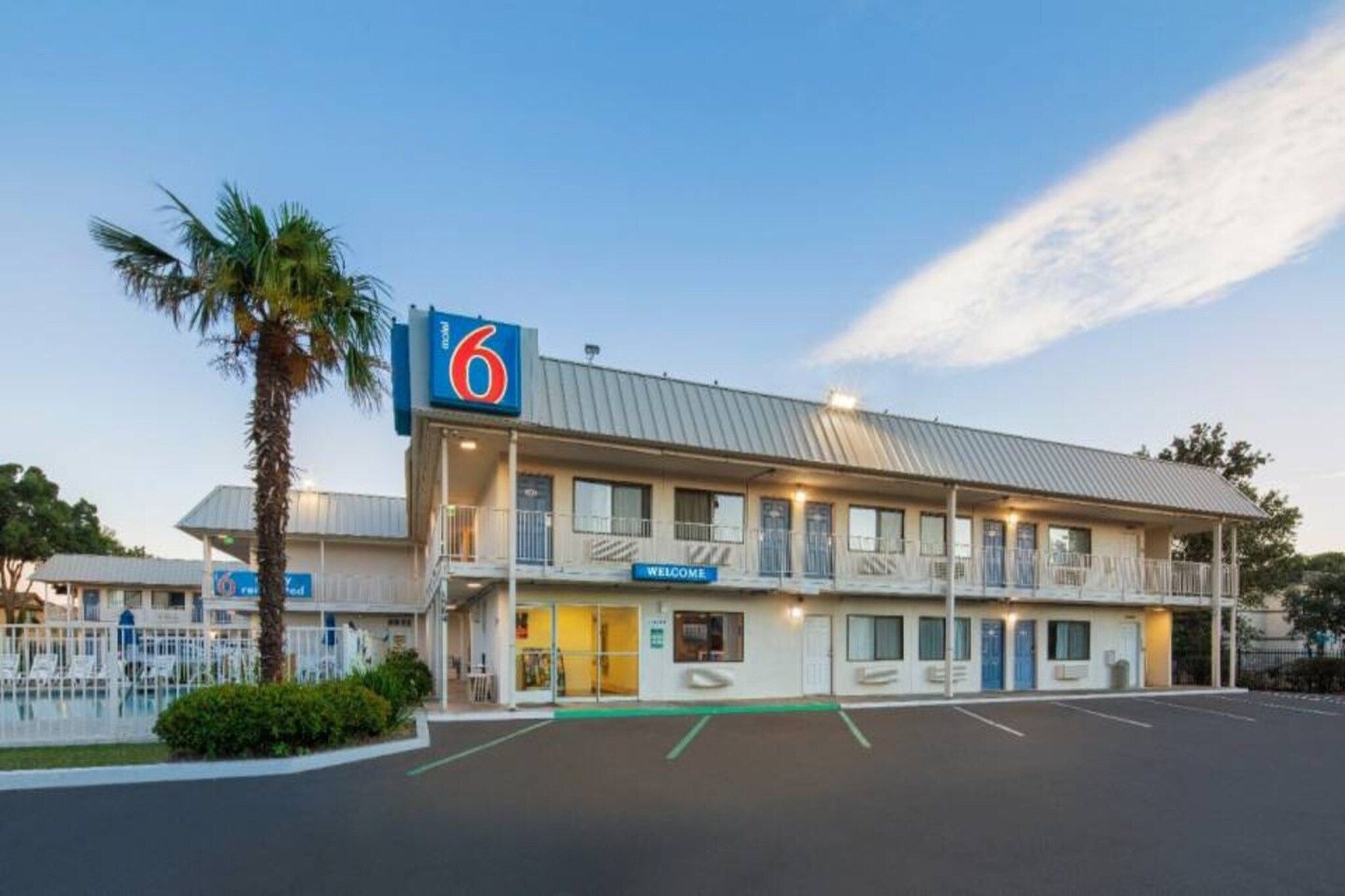 A motel with a '6' sign, a 'Welcome' sign, and a parking lot.