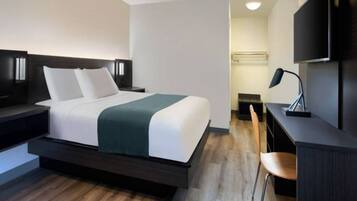 A modern hotel room with a bed, bedside tables, a desk, a chair, and a TV.