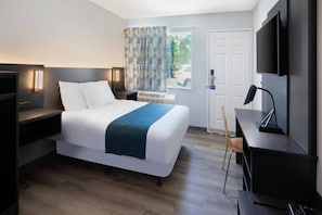 Een hotelkamer met een bed, nachtkastjes, een bureau, een stoel, een televisie en een deur.