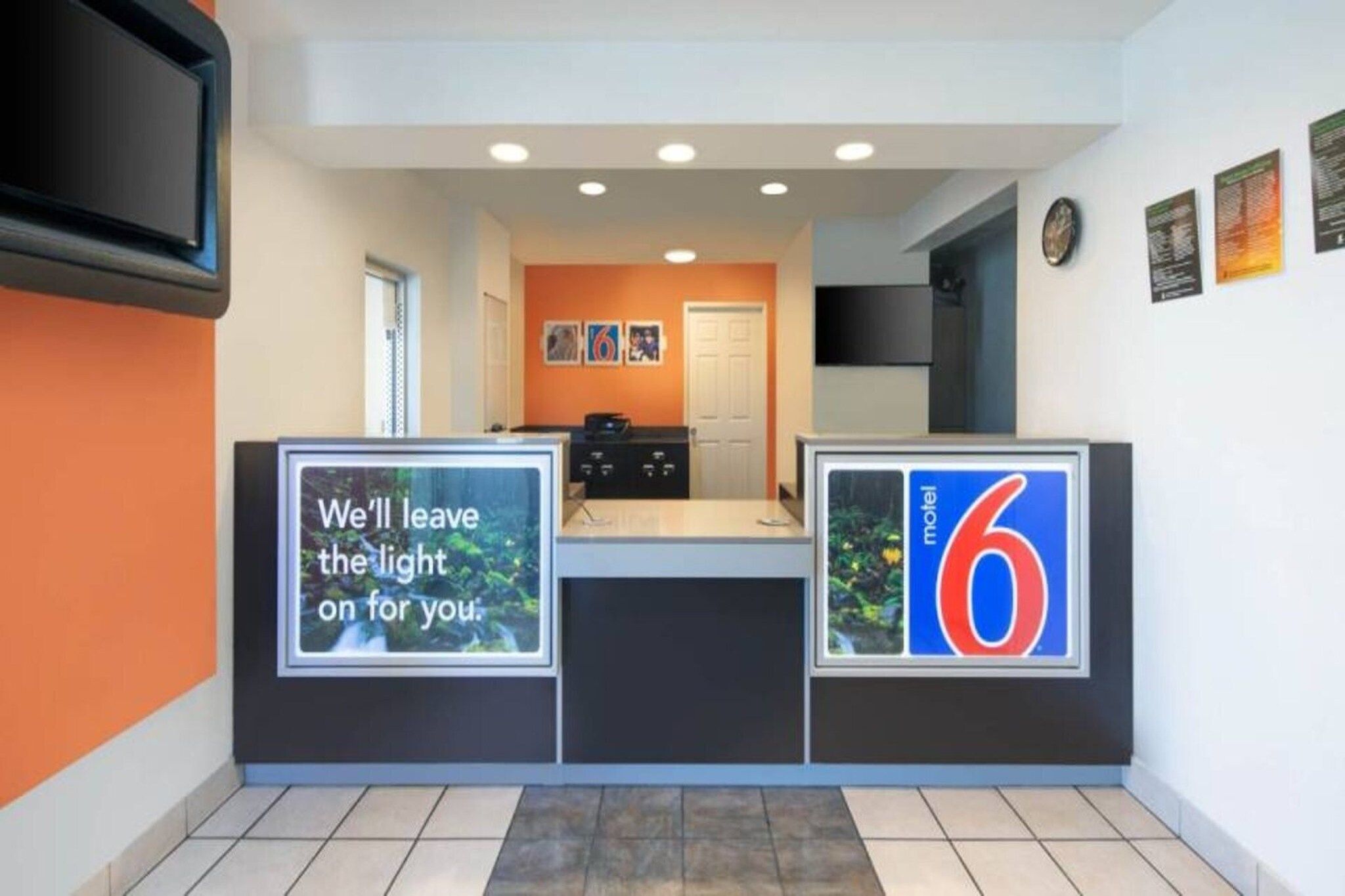 A hotel reception area with a counter, a door, and a wall with a number '6' sign.