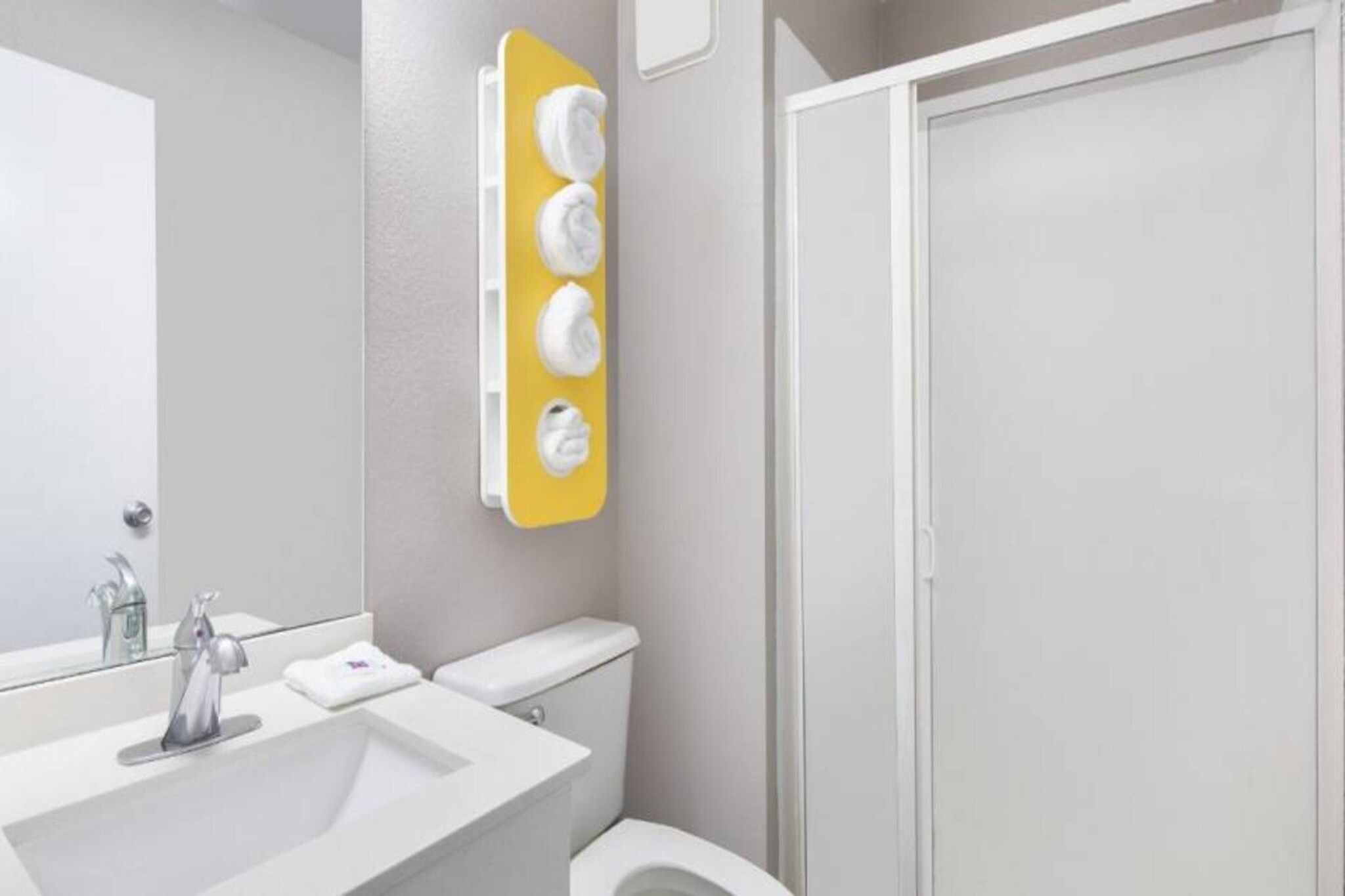 A bathroom with a white sink, a mirror, a toilet, and a shower.